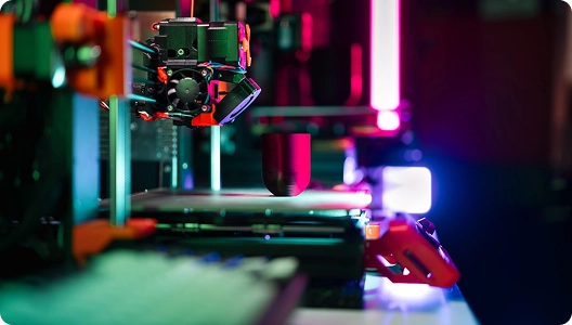 Een 3D-printer in werking, verlicht door fel neonroze en blauwe lampen. Het tafereel is futuristisch en hightech, en benadrukt precisie en innovatie.